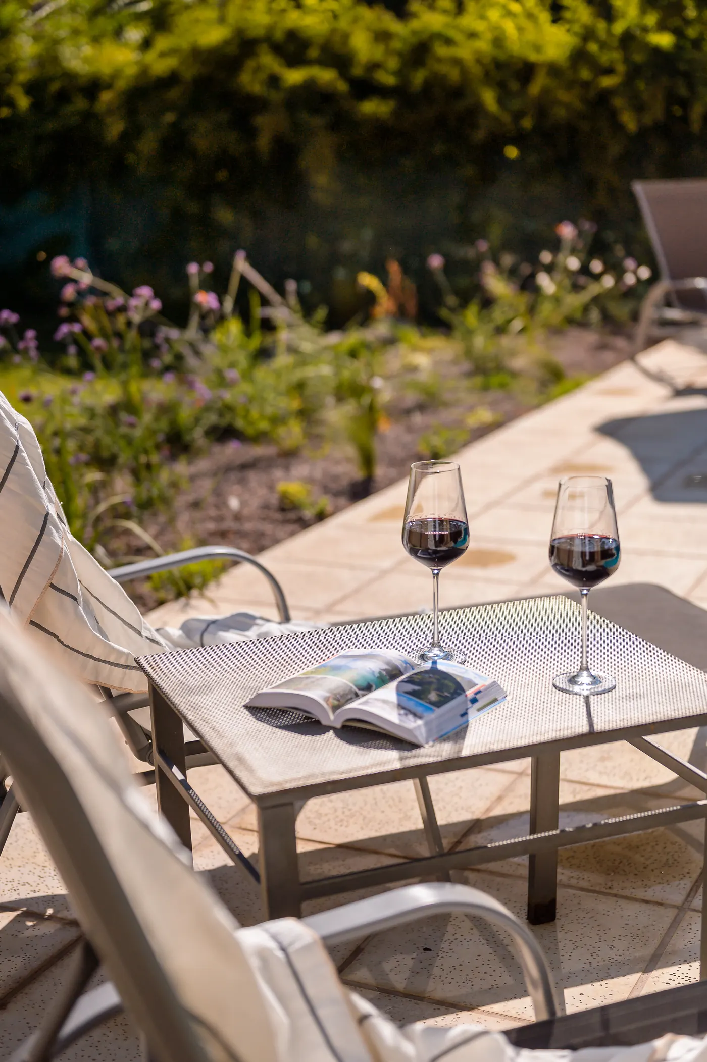 Patio con reposeras, una revista abierta y dos copas de vino tinto